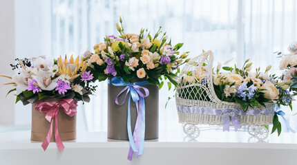3 flower arrangement lined up in a row for congratulations on the birth of a child. Beautiful bouquets in baskets for congratulations a basket in the form of a stroller with flowers inside