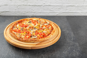 delicious pizza with chicken, mushrooms, cheese, tomatoes and corn on a concrete background