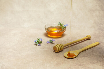 drizzle of honey dripping on cheese slices with fresh rosemary branches in bloom and a glass bowl with rosemary honey.