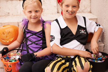 Siblings, portrait and halloween costume on stairs, candy and happiness in childhood. Boy, girl or...