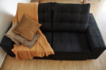 sofa preto decorado com almofadas em tons de marrom em sala aconchegante e moderna 