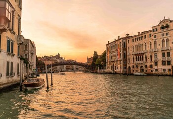 Amazing old wooden bridge over canal water in Venice Italy with sunset light over palaces