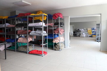Clothing on the shelves in the warehouse. Selection of textiles for sale. Production and storage.