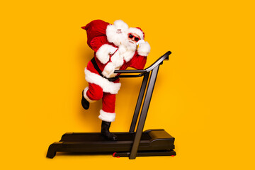 Full length photo of funky santa claus north pole character in sport gym isolated on yellow color background