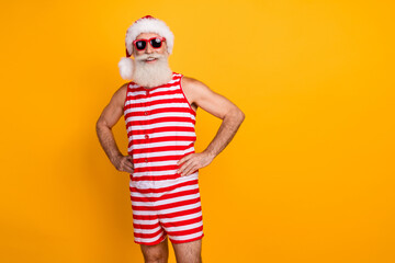 Fototapeta na wymiar Photo of positive elderly guy wear swimsuit hat sunglass celebrating new year journey empty space isolated yellow color background