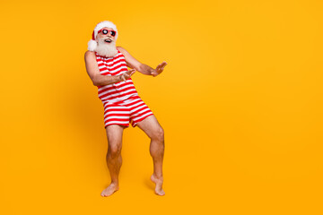 Full length photo of cool cheerful elderly guy wear new year swimsuit hat sunglass having disco fun empty space isolated yellow color background
