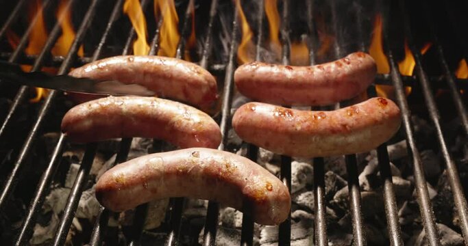 Juicy sausages sizzle on grill under flames. Cook expertly flips sausages with tongs. Their smoky sweetness and delicate texture make them perfect addition to any grilled feast. Template for title