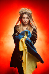 Beautiful Ukrainian woman in a national Ukrainian dress with a blue and yellow flag of Ukraine. The concept of military operations in Ukraine, national clothing and female power.