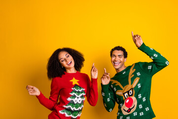 Photo of dreamy sweet lady guy wear new year ugly print sweaters dancing pointing empty space isolated yellow color background