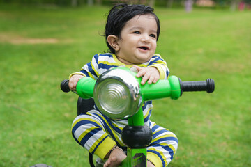 Cute little toddler rides the tricycle. Toddler using bike at park or garden. Learning to ride bike concept.