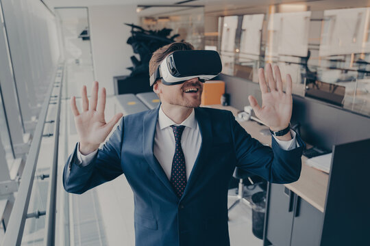 Exited businessman stands in office interior after finishing workday in virtual reality VR headset