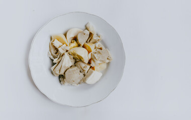 Top view of Siomay Bandung or steamed dumplings, traditional Indonesian street snacks without peanut sauce and soy sauce, served on a white plate. Copy space. Indonesian culinary food concept.