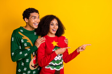 Photo of sweet impressed guy girl dressed christmas ugly print pullovers pointing finger empty space isolated yellow color background