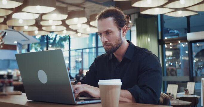 Concentrated man sitting in coffee shop improving digital skills at laptop working. Digital skills. Set of technical abilities required for freelancers to effectively perform tasks using computer. 