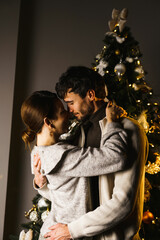 Happy family father, mother and son decorate the New Year tree, have fun, dance and unpack gifts. Christmas and New Years Eve concept. Vertical shot