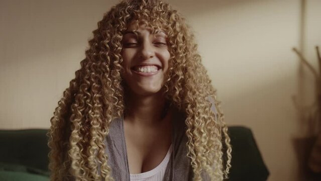 Young transsexual woman sitting on bed smiling and flicking her hair. Cinematic 4k.