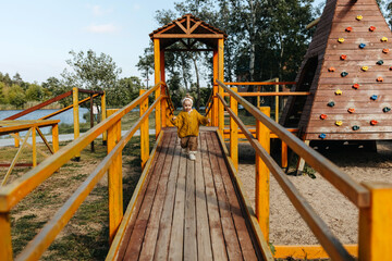Child running on a wooden bridge at a playground outdoors.