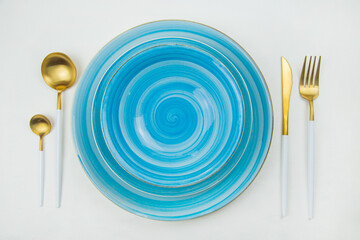 Two bright blue serving plates with a spiral pattern, gold - white serving devices are located on...