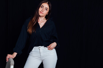 Portrait of a beautiful brunette woman in black clothes on a dark background