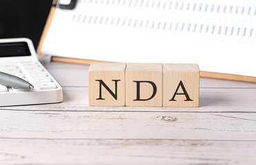 NDA word on a wooden block with clipboard and calculator