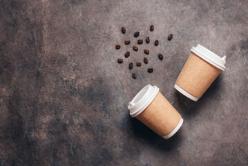 Coffee in paper cups with coffee beans on a dark brown background. Top view, flat lay. Disposable...