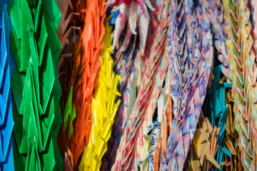 Strings of colourful folded origami paper cranes in Hiroshima peace park, Japan. If you fold a 1000...