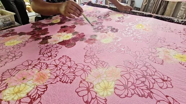 Making batik by drawing freehand patterns on fabric in Thailand.