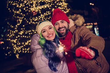 Portrait of lovely peaceful partners arm hold bengal lights stick magic christmastime fairy capital center tree garland outside