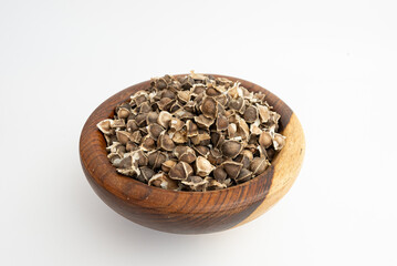 moringa seeds on a wooden plate isolated on a white background
