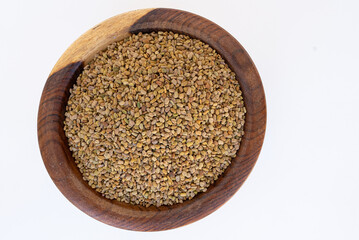fenugreek seeds on a wooden plate isolated on a white background