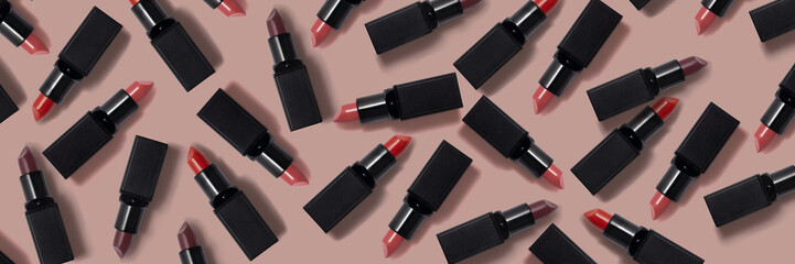 Lot of lipsticks with black tubes on the beige surface. Lipsticks as a background - obrazy, fototapety, plakaty
