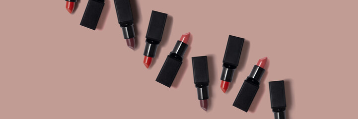 Line, row of red, pink and dark red lipsicks on the beige wide banner.Empty space