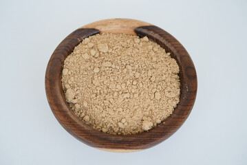 Ginger Root Powder on a wooden plate isolated on a white background
