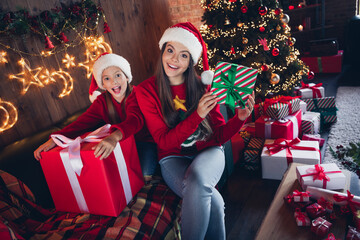 Fototapeta na wymiar Photo of shiny impressed small sisters wear red ugly print new year pullover packing gifts indoors apartment room