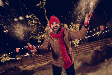 Photo of funny student guy wear warm knitted accessories red scarf with cap throwing winter snow in...