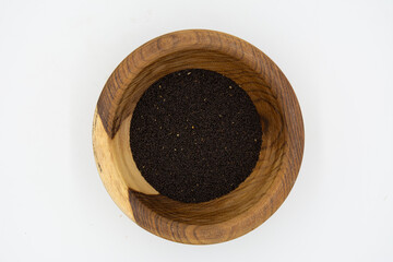 Nigella sativa seeds on a wooden plate isolated on a white background