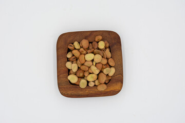 Dried fava beans on a wooden plate isolated on a white background
