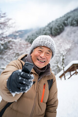 Fototapeta na wymiar Aging Gracefully in Nature: Self-Portrait of Senior Asian Gentleman in Snowy Mountain Landscape.