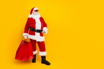 Full length photo of santa red costume sunglass touch belt look empty space to buy shopping mall bags isolated on yellow color background