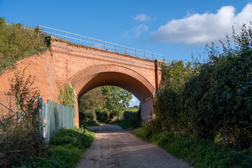 Fototapeta na wymiar Cromer, Norfolk, UK – November 6 2023. Railway bridge in the countryside against a bright blue sky