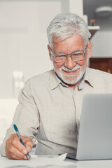 Aged remote worker. Concentrated senior male in glasses work on laptop from home office read email...