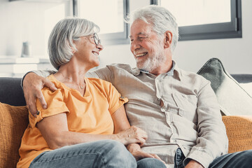 Happy laughing older married couple talking, laughing, standing in home interior together, hugging with love, enjoying close relationships, trust, support, care, feeling joy, tenderness. - obrazy, fototapety, plakaty