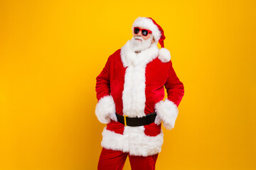 Portrait of confident eccentric santa put hands waist empty space new year proposition isolated on yellow color background