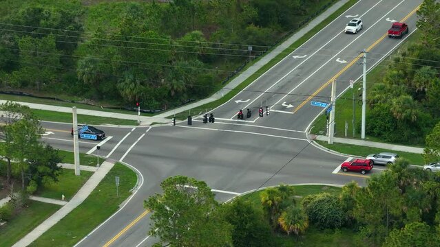 Suburban road with driving vehicles at intersection with traffic lights. Town transportation in the USA. American rural traffic