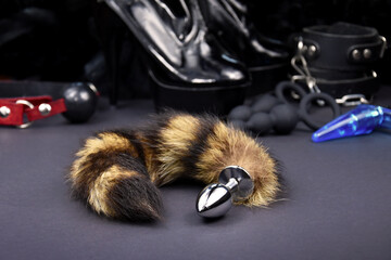 Anal plug animal tail on a dark background close-up stock photo images. Set of erotic toys for BDSM images. Adult sex toy, fur butt plug, handcuffs and high heel shoes images - obrazy, fototapety, plakaty