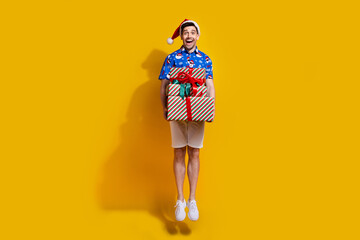 Full size portrait of excited astonished guy jumping arms hold pile stack newyear giftbox isolated on yellow color background