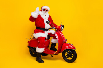 Full body profile photo of charismatic aged santa drive bike arm palm waving hi new year greetings...