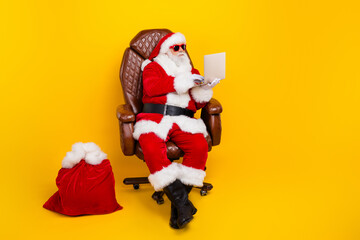 Full body photo of aged santa claus sit leather chair use netbook christmas gifts bag empty space...