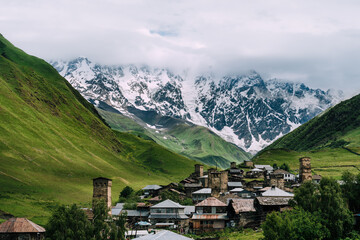 Panoramic view of medieval towers and Shkhara peak in village Ushguli in the Caucasus Mountains, Georgia.Stone towers and ancient houses in Ushguli, Georgia. UNESCO site, popular tourist destination. - obrazy, fototapety, plakaty