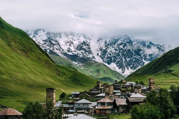 Fotobehang Panoramic view of medieval towers and Shkhara peak in village Ushguli in the Caucasus Mountains, Georgia.Stone towers and ancient houses in Ushguli, Georgia. UNESCO site, popular tourist destination. © Ksenya
